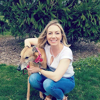 Woman smiling at camera with dog free of breast pain