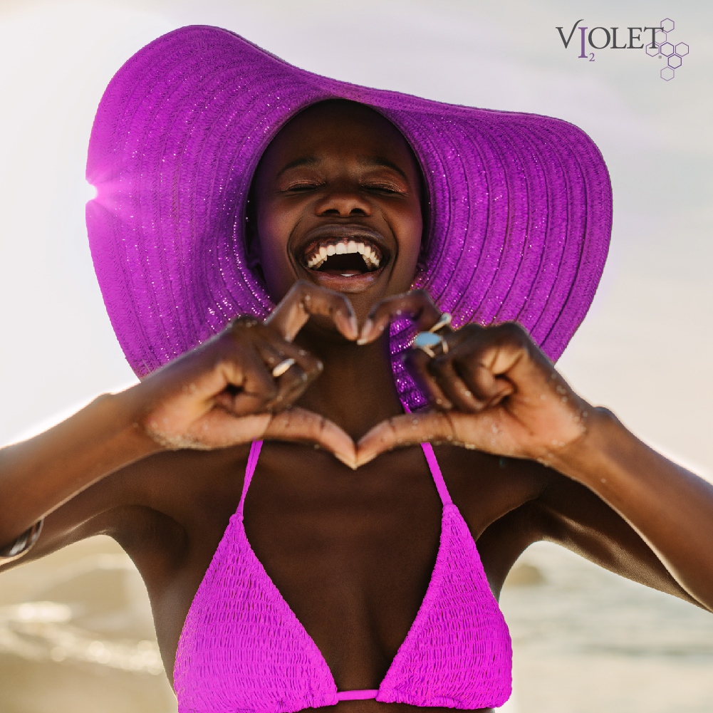 black woman in purple hat and bikini at the beach